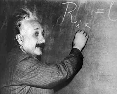 Albert Einstein writing on a blackboard.