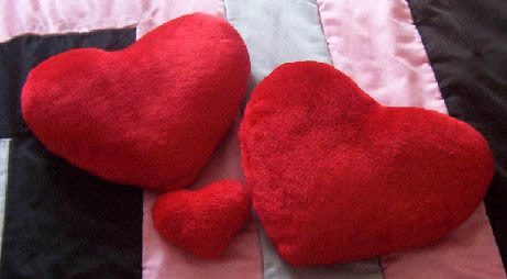 Tre cuscini di cuori rossi.