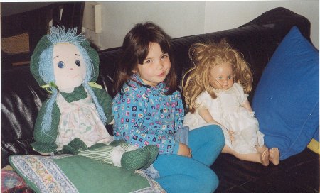 Menina em um sofá com duas bonecas